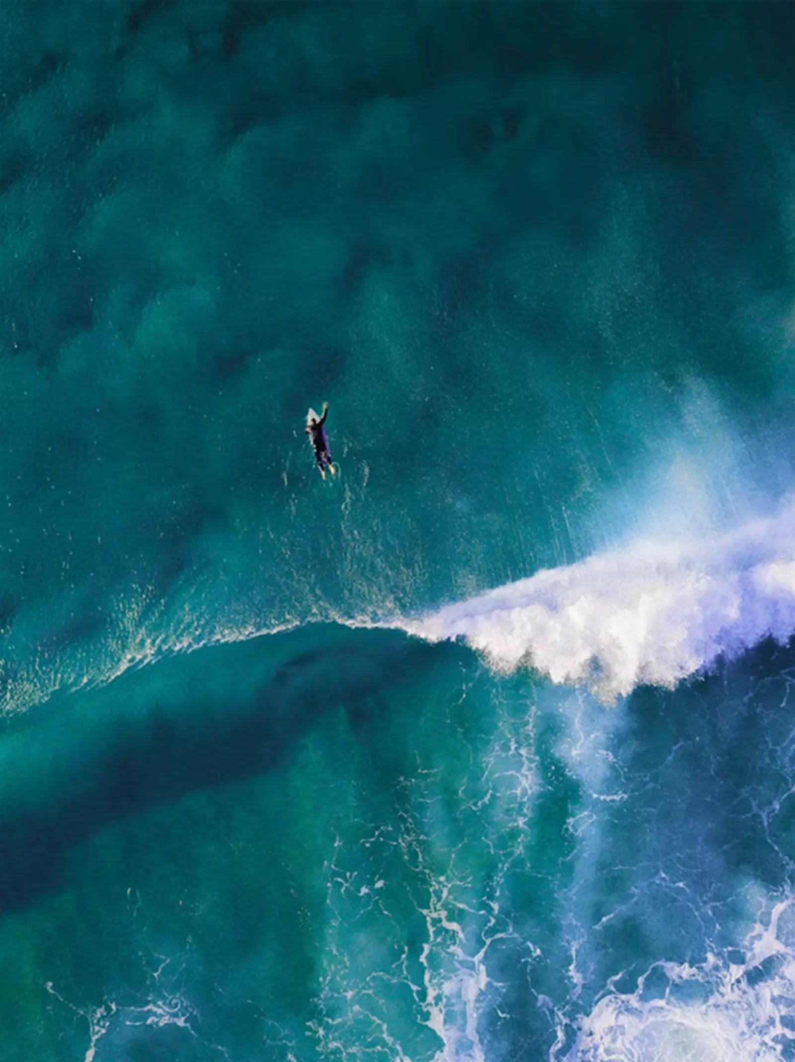 Surfer beneath a blue ocean wave